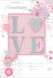 This anniversary card is a gentle tribute to lasting love, designed in a palette of tender blush pinks, soft whites, and refined silvery notes that evoke a peaceful evening in Blackfriars after the city's bustle has faded. At the centre, the word LOVE is crafted in raised, glitter-brushed lettering, the sparkle subtle and sophisticated rather than flashy. The textured surface seems made to be touched, like the embossed ribbon on a beautifully wrapped bouquet awaiting delivery to a quiet flat off Ludgate Hill. Behind these letters, the background blush is slightly deeper, giving a sense of warmth and focus, while the rest of the card softens into paler pink tones. Swirling out from the central word, a series of delicate blooms, fine leaves, and gently curling vines forms a loose frame. These floral motifs are drawn with thin, graceful lines and shaded in gentle gradients of pink, white, and grey, some edged with a whisper of silver that catches the light like morning sun on dewy petals. The arrangement has the feel of a florist's artistic flourish - almost as though these flowers could be gathered into a small, romantic posy. Lower on the card, a heartfelt anniversary sentiment is written in flowing, cursive script, its letters slender and poised, echoing the movement of the surrounding vines. The spacious layout and soft tones give the whole design a light, dreamlike quality, like a cherished memory of a shared walk by the Thames. It's a card that visually expresses quiet devotion, care, and the comfort of a love that has grown deeper with time.